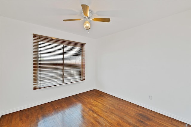 spare room featuring a ceiling fan, wood-type flooring, and baseboards