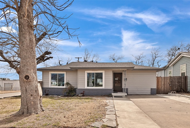 ranch-style home featuring concrete driveway, brick siding, and fence