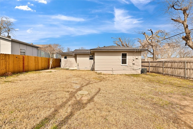 rear view of house with a fenced backyard and a yard