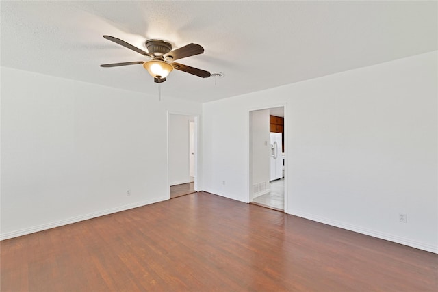 empty room with baseboards, visible vents, a ceiling fan, wood finished floors, and a textured ceiling