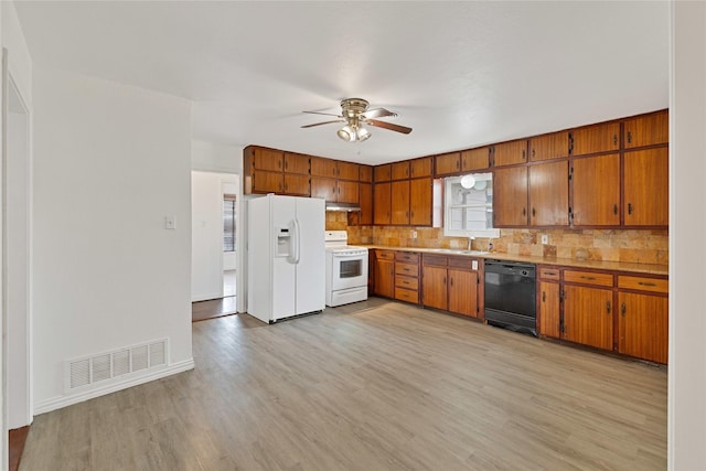 kitchen featuring brown cabinetry, white appliances, visible vents, and light wood finished floors