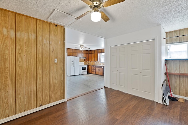 unfurnished living room featuring a textured ceiling, wood finished floors, and wooden walls