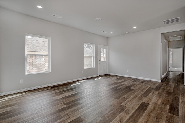 empty room with dark wood-style floors, baseboards, visible vents, and recessed lighting