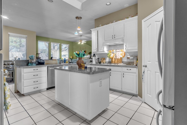 kitchen with white cabinets, under cabinet range hood, stainless steel appliances, and light tile patterned flooring