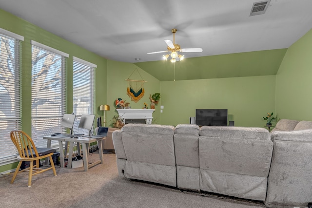 carpeted living area featuring ceiling fan, a fireplace, visible vents, and vaulted ceiling