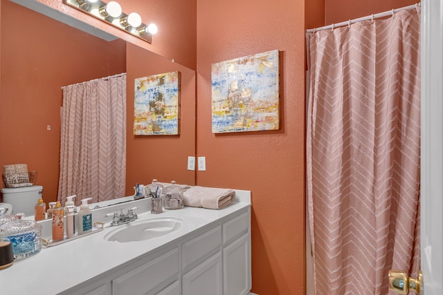 bathroom featuring a shower with shower curtain, a textured wall, vanity, and toilet