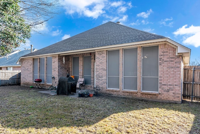 back of property featuring fence private yard, roof with shingles, a lawn, and a patio