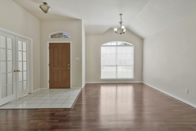 living room featuring a notable chandelier, wood finished floors, visible vents, baseboards, and vaulted ceiling