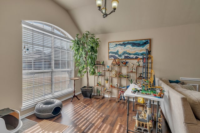 interior space with lofted ceiling, a notable chandelier, baseboards, and wood finished floors