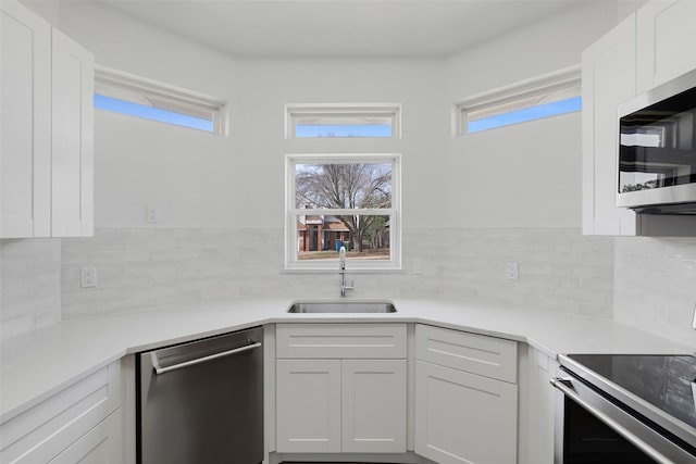 kitchen featuring appliances with stainless steel finishes, a wealth of natural light, white cabinets, and a sink