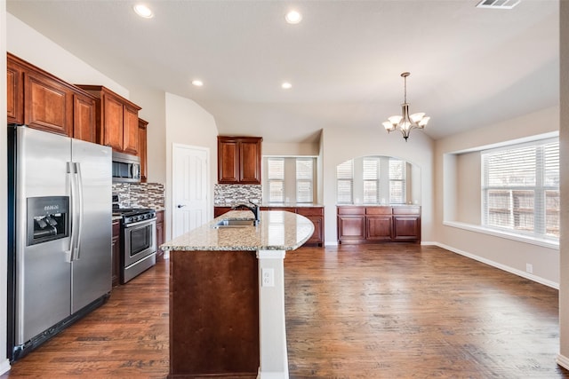 kitchen with stainless steel appliances, dark wood-type flooring, vaulted ceiling, a sink, and light stone countertops