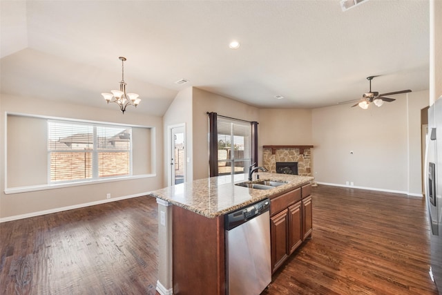 kitchen with a fireplace, a sink, open floor plan, stainless steel dishwasher, and light stone countertops