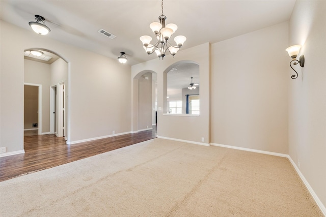 spare room featuring arched walkways, visible vents, carpet, and ceiling fan with notable chandelier