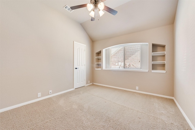 carpeted empty room with vaulted ceiling, built in shelves, visible vents, and baseboards