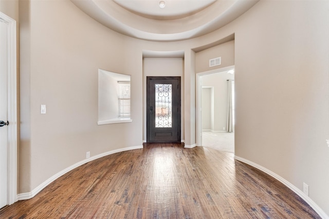 foyer with baseboards, a high ceiling, visible vents, and wood finished floors