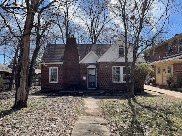 tudor home featuring brick siding and a chimney