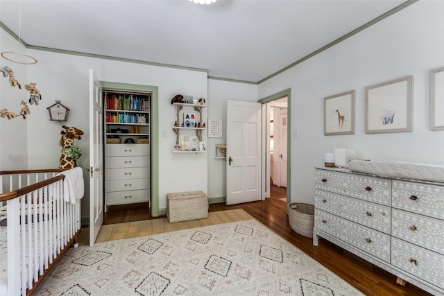 bedroom featuring a nursery area and wood finished floors