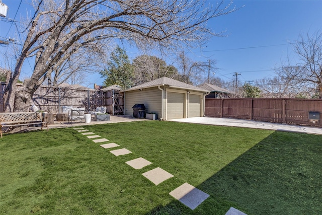 view of yard featuring a garage, a fenced backyard, a patio, and an outbuilding