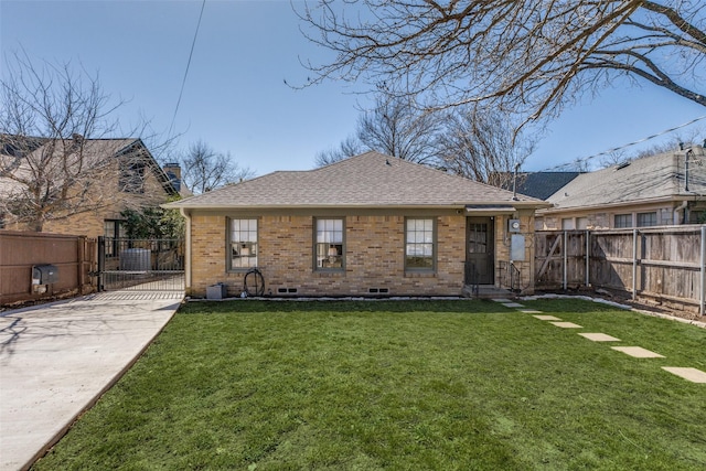 back of property with a shingled roof, a gate, fence, a yard, and brick siding