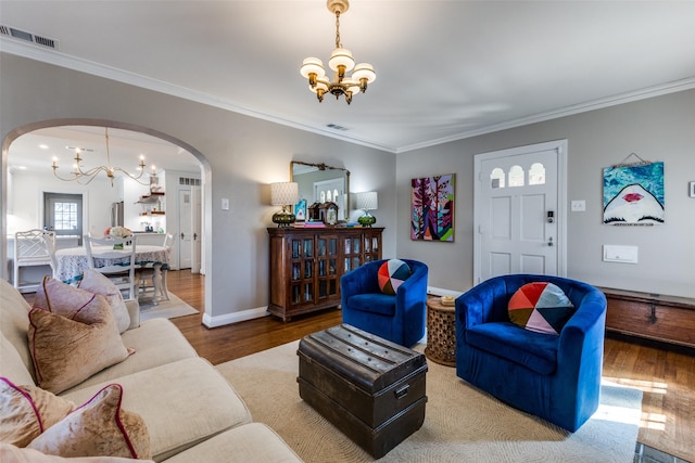 living area with a chandelier, arched walkways, visible vents, and wood finished floors