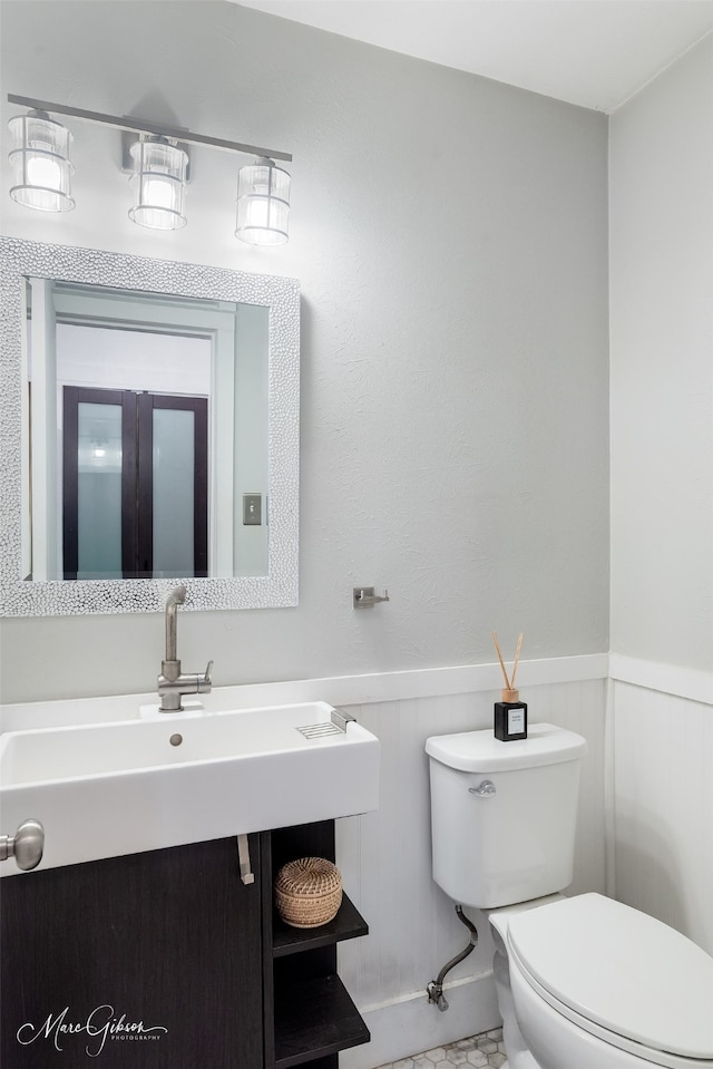 bathroom with a wainscoted wall, vanity, and toilet