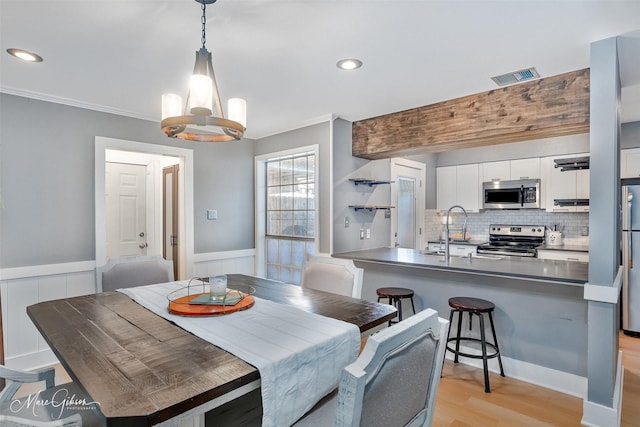 dining room with visible vents, crown molding, and wainscoting