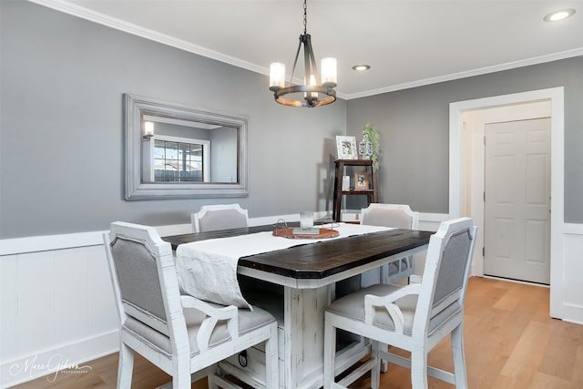 dining space featuring a wainscoted wall, a notable chandelier, crown molding, recessed lighting, and light wood-type flooring