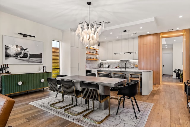 dining room with light wood-style flooring, visible vents, indoor wet bar, and recessed lighting