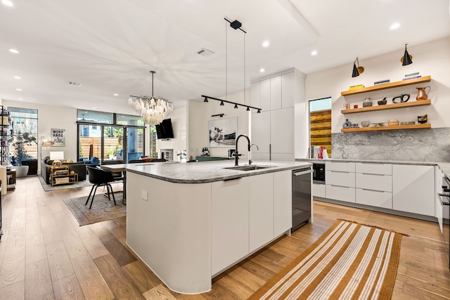 kitchen with a center island with sink, white cabinets, a sink, modern cabinets, and light wood-type flooring