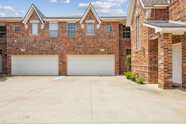 view of front of house with brick siding, a garage, and concrete driveway