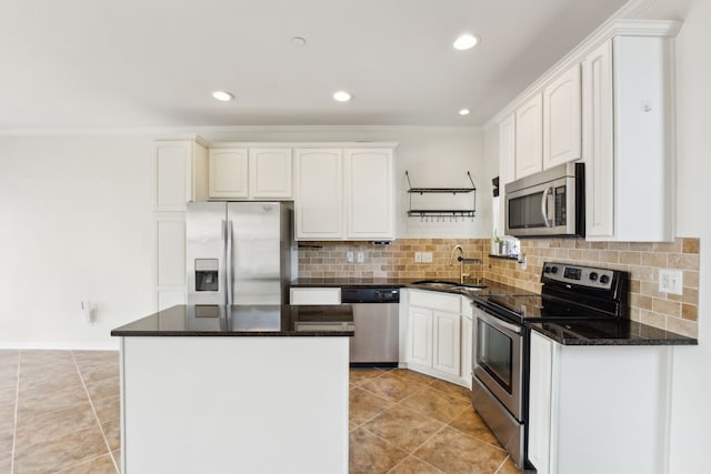 kitchen with crown molding, appliances with stainless steel finishes, a center island, tasteful backsplash, and a sink