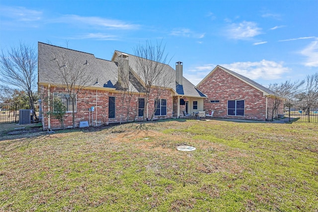 view of front of home featuring brick siding, fence, roof with shingles, a front lawn, and a chimney