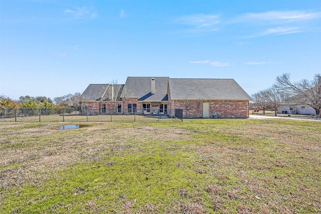 back of property featuring a yard, brick siding, and fence