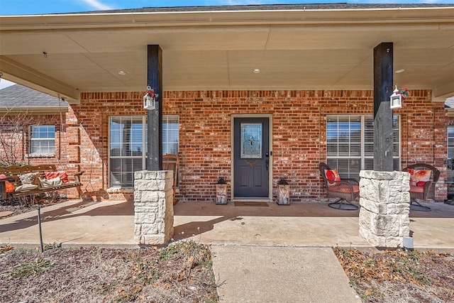 entrance to property with brick siding and a porch