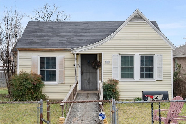 view of front of house featuring a shingled roof, a fenced front yard, and a front yard