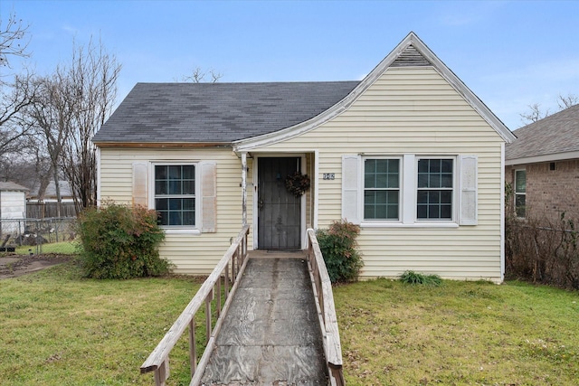 bungalow with a front lawn, roof with shingles, and fence