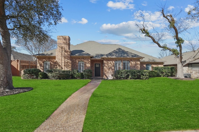 single story home with brick siding, a chimney, a shingled roof, a front yard, and fence