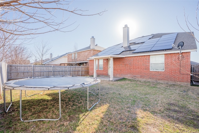 view of yard featuring a trampoline, a fenced backyard, and a patio