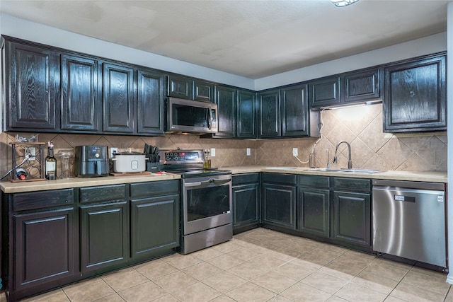 kitchen featuring light tile patterned floors, tasteful backsplash, stainless steel appliances, light countertops, and a sink