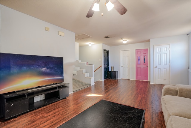 living room with stairs, wood finished floors, a ceiling fan, and attic access