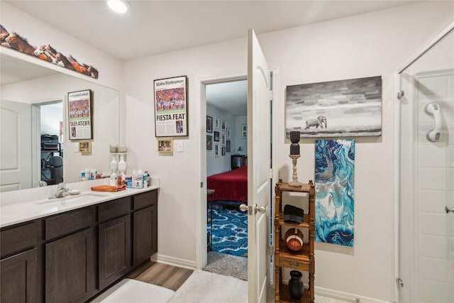 bathroom with connected bathroom, vanity, baseboards, and wood finished floors