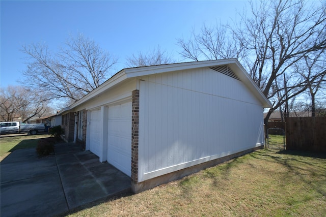 view of side of home with a lawn, an attached garage, and fence