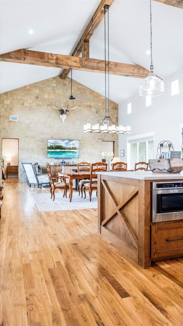 kitchen featuring high vaulted ceiling, light wood-style flooring, beamed ceiling, and oven