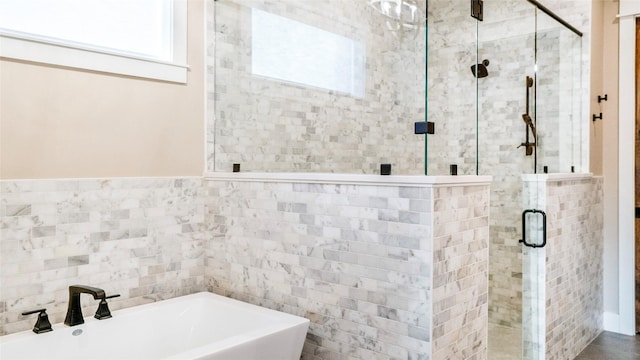 full bath with a stall shower, a soaking tub, a sink, and tile walls