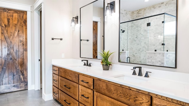 bathroom featuring double vanity, a stall shower, a sink, and tile patterned floors