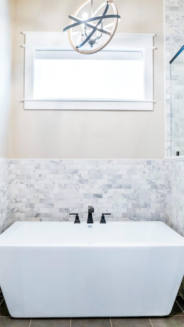 full bathroom with a freestanding bath, a chandelier, tile walls, and tile patterned floors