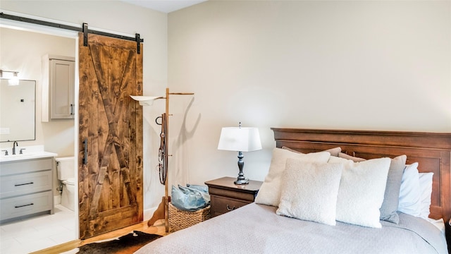 bedroom featuring a barn door, connected bathroom, and a sink