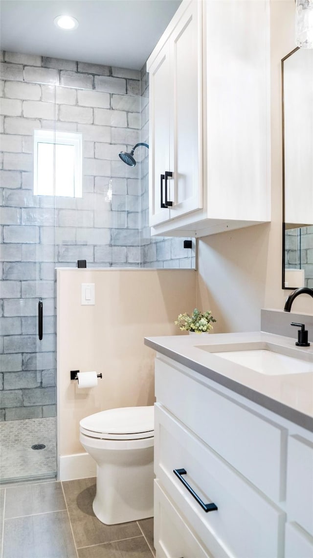 bathroom featuring a shower stall, toilet, and vanity