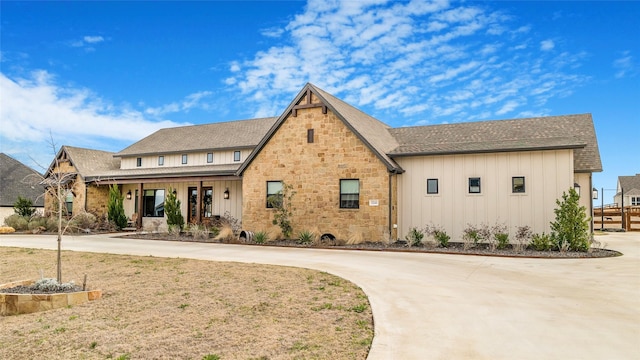 view of front of property featuring stone siding, board and batten siding, and concrete driveway