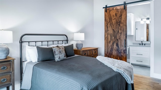 bedroom featuring a barn door, a sink, and wood finished floors